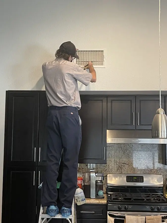 Technician inspecting an air vent during HVAC service in Coffeyville
